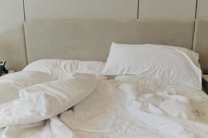 onopgemaakt beddengoed lakens en kussen. onopgemaakt rommelig bed na comfortabel slaap concept foto