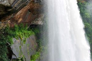 waterval groot en hoog stroom rivier- berg met klif steen grot in de oerwoud tropisch foto
