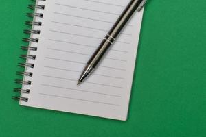 een notitieboekje met een blanco bladzijde en een pen resting Aan het foto