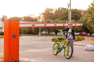 weinig meisje Aan een fiets fiets in de buurt de barrière foto