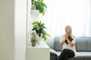 meisje bidden. kant visie van mooi jong blond haar- vrouw bidden Bij huis foto