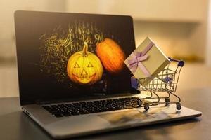 kar vol van cadeaus voor halloween in de buurt een pompoen. pompoen in een laptop foto