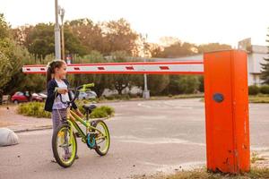 weinig meisje Aan een fiets fiets in de buurt de barrière foto
