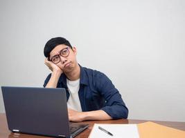 Aziatisch zakenman zittend Bij werkplaats tafel voelt geprobeerd en verveeld met werk foto