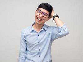 Aziatisch Mens slijtage bril voelt verlegen houden zijn hoofd met glimlach geïsoleerd foto