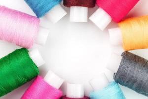 naaien draden van verschillend kleuren Aan haspels Aan een wit achtergrond in een cirkel. foto