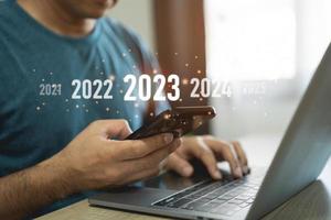 nieuw jaar 2023 concept. begin gelukkig nieuw jaar 2023. zakenman investeerders gebruik makend van laptop en mobiel telefoon tintje scherm virtueel 2023 jaar diagram, bedrijf planning, strategie, bedrijf trends, investering. foto