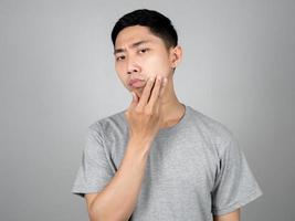 Aziatisch Mens controle huid zijn gezicht voelt bezorgd geïsoleerd foto