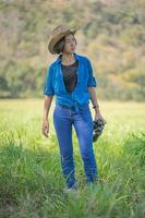 vrouw slijtage hoed en houden verrekijker in gras veld- foto