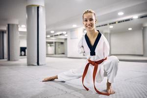gelukkig zonder armen sportvrouw beoefenen taekwondo in krijgshaftig kunsten club en op zoek Bij camera. foto