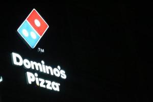 bekasi, Indonesië in juli 2022. domino's pizza logo schijnend helder Bij nacht tegen de donker nacht lucht. foto