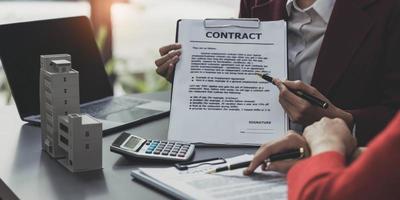 makelaar biedt hand voor klant teken overeenkomst contract handtekening voor koop of verkoop huis. onroerend goed concept contact overeenkomst concept foto