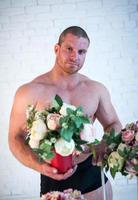 sexy mannetje atleet met boeketten van bloemen Aan wit achtergrond foto