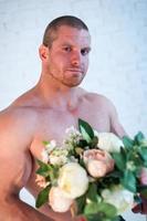 sexy mannetje atleet met boeketten van bloemen Aan wit achtergrond foto