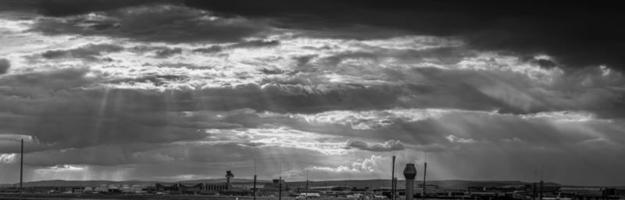 panorama zwart en wit beeld van Frankfurt luchthaven tegen indrukwekkend lucht met wild wolk formaties en zon stralen foto