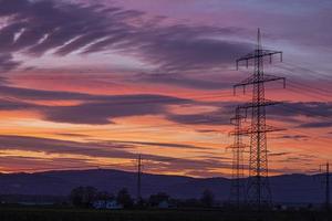 beeld van een kleurrijk en hoog contrast zonsopkomst met helder wolk formaties en contouren van macht polen foto