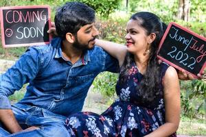 indiase paar poseren voor zwangerschaps baby shoot. het paar poseert in een gazon met groen gras en de vrouw pronkt met haar babybuil in de Lodhi-tuin in New Delhi, India foto