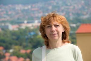 portret van een mooi oud vrouw tegen de backdrop van een typisch Europese stad- met rood daken. mooi landschap met een wazig achtergrond. foto