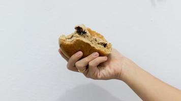 vrouw hand- Holding een chocola donut tegen een wit achtergrond foto