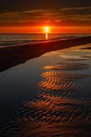 patronen in de zee zand Bij zonsondergang foto