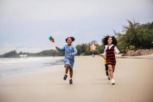 gelukkig groep van Afrikaanse Amerikaans kinderen spelen Aan de strand tegen Doorzichtig lucht foto