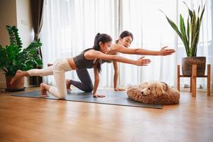 Aziatisch jong moeder onderwijs haar dochter naar yoga houding en oefening samen met hun hond foto