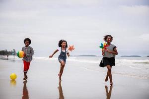 groep van jong Afrikaanse Amerikaans kinderen rennen Aan een tropisch strand. etnisch verschillend concept foto