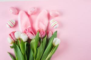 Pasen grappig samenstelling. roze achtergrond met tulpen, Pasen eieren, pluizig konijn oren. vlak leggen, top visie foto