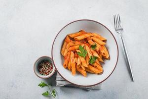 penne pittig pasta met tomaat sausen en papper in bord Aan steen achtergrond tafel. top visie. foto