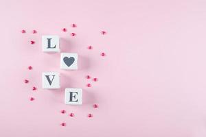 liefde bericht geschreven in wit houten blokken Aan roze achtergrond. roze snoep harten. vlak leggen, kopiëren ruimte foto