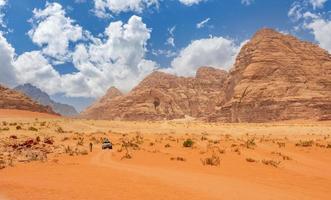 oranje zand en kliffen van wadi rum woestijn met toerist auto in de achtergrond, Jordanië foto