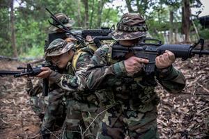 team van legersoldaat met machinegeweer bewegen in het bos, Thaise militie soldaat in gevechtsuniformen in het bos, dwalen door de patrouille glooiend in het regenwoud. foto