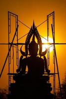 silhouet Boeddha standbeeld tussen creëren en gebouw werkwijze, Bij buitenshuis veld- met de zon reeks en schemering periode tijd., Thailand. foto