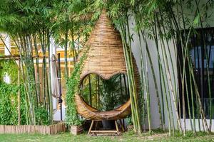 hart vorm en cocon mini paviljoen kom tot rust zone in tuin, zijn rieten mandenmakerij door bamboe stok. foto