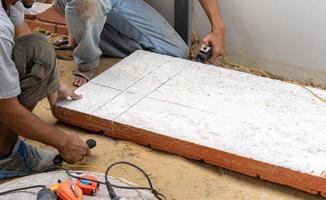 twee arbeid besnoeiing de polyurethaan schuim steen bord door warmte draad gereedschap voor installeren in Aan de muur. foto