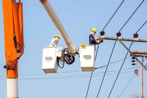 elektriciens werken Aan kabel auto naar reparatie de macht lijn onder licht blauw lucht achtergrond. foto