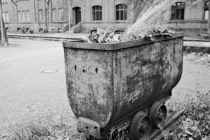 roestig oud steenkool vrachtwagen in voorkant van industrieel gebouw foto