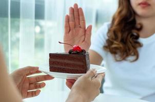 de Dames gebruikt naar Duwen de taart bord met de mensen. Doen niet eten desserts voor gewicht verlies. foto