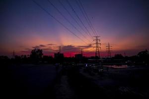 hoog Spanning elektrisch pylonen silhouet met kleurrijk landschappen na zonsondergang foto