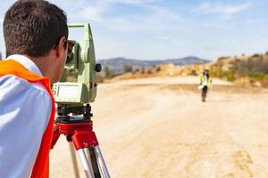 landmeter ingenieur arbeider maken meten met theodoliet uitrusting Bij bouw plaats gedurende weg werken foto