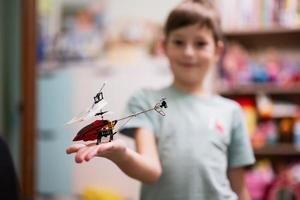 jongen shows speelgoed- helikopter Aan de afgelegen controle in kinderen kamer. foto