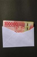 portret van Indonesisch roepia bankbiljetten waard idr 100.000 in een wit envelop geïsoleerd Aan zwart achtergrond foto