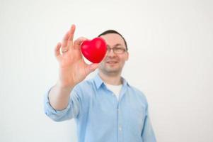 portret van grappig Mens Holding klein rood hart, op zoek Bij camera met opgewonden gelaats uitdrukking, romantisch gevoelens. valentijnsdag dag, verjaardag, liefdadigheid foto