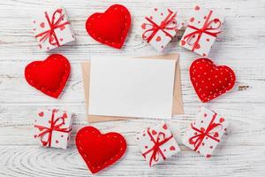 envelop mail met rood hart en geschenk doos over- wit houten achtergrond. Valentijn dag kaart, liefde of bruiloft groet concept foto