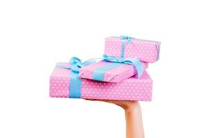 vrouw handen geven verpakt reeks van Kerstmis of andere vakantie handgemaakt Cadeau in roze papier met blauw lintje. geïsoleerd Aan wit achtergrond, top visie. dankzegging geschenk doos concept foto