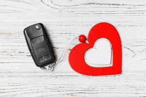 top visie van een Cadeau voor Valentijnsdag dag Aan houten achtergrond. dichtbij omhoog van auto sleutel en hart. verrassing concept voor een vakantie foto