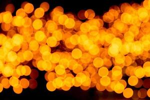 feestelijk abstract goud achtergrond met bokeh onscherp en wazig veel ronde geel licht Aan Kerstmis donker achtergrond foto