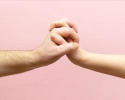 jong vrouw en Mens Holding handen samen Aan roze achtergrond. foto