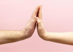 jong vrouw en Mens Holding handen samen Aan roze achtergrond. foto