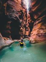 vrouw toerist wandelen in water in beroemd rivier- Ravijn van wadi mujib in verbazingwekkend gouden licht kleuren. wadi mujib reizen bestemming in Jordanië foto